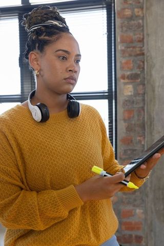 Focused Professional With Headphones Reviewing on Tablet in Modern Office