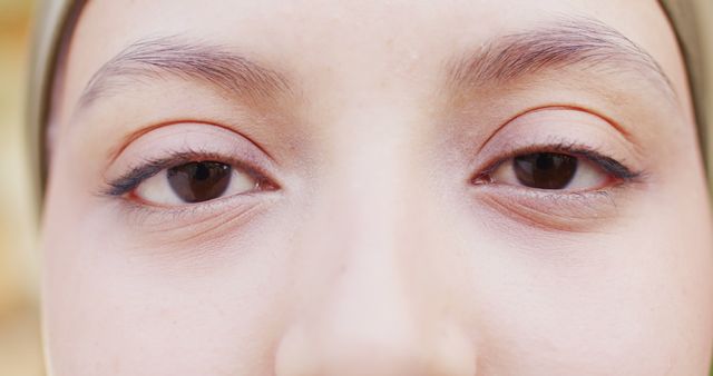 This close-up shows a young woman's eyes with a neutral expression, highlighting natural beauty and clear skin. Useful for beauty products, skincare promotions, or cultural representation. Ideal for eye makeup ads, meditation apps, and health and wellness blogs.