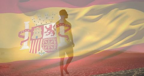 Silhouette of Man Walking on Beach Overlaid with Spanish Flag