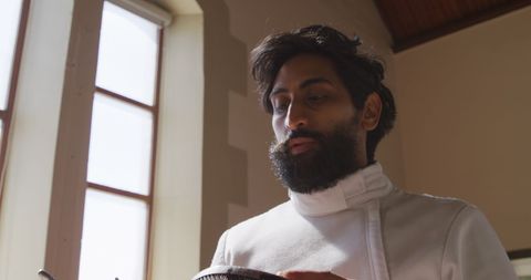 Fencing Athlete Preparing with Focus in Sunlit Room