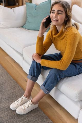 Teen Girl Chatting Happily on Mobile While Lounging on Sofa