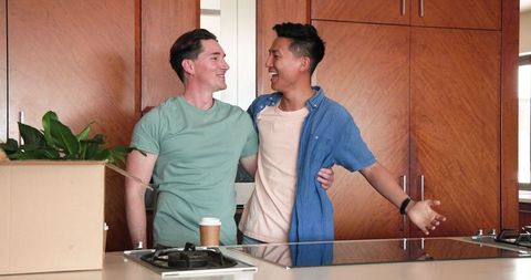 Happy Diverse Couple Embracing in New Kitchen with Coffee