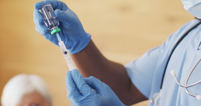 Image shows a close-up of a healthcare worker wearing blue gloves while holding a syringe and vaccine vial. Ideal for medical and healthcare promotions, vaccination campaigns, COVID-19 awareness materials, and public health information.