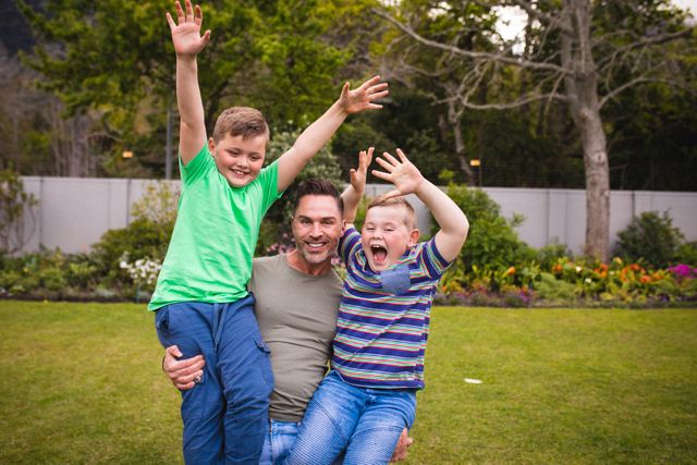 Father and two sons enjoying playful moment in garden. Perfect for family-oriented content, parenting blogs, advertisements promoting outdoor activities, and articles on fatherhood and family bonding.