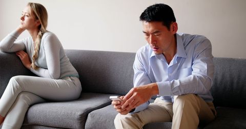 Distant Couple Sitting on Sofa with Phone Interaction