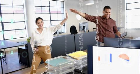 Young professionals high-fiving in modern open-plan office celebrating teamwork and productivity