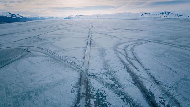 Stretching frozen expanse leading long ice track toward distant arctic horizon