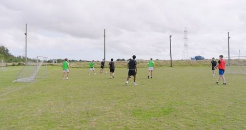 Diverse Teen Boys Playing Soccer on Outdoor Field in Team Practice