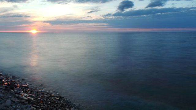 Tranquil Sunset Over Calm Ocean with Rocky Shores - Download Free Stock Photos Pikwizard.com
