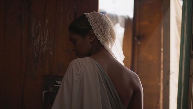 Contemplative woman in doorway showing bare back with lace scarf and draped shawl