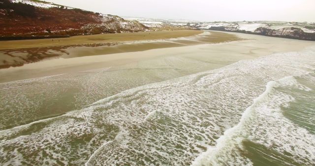Aerial view of a coastal landscape showing waves lapping onto a sandy beach, with copy space - Download Free Stock Photos Pikwizard.com