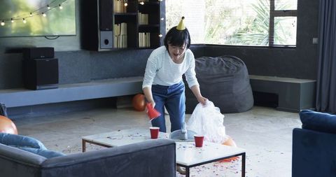 Senior Woman Tidying Up After Party in Modern Living Room