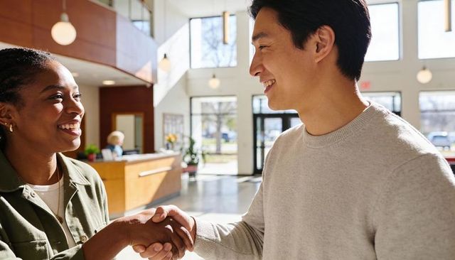 Shaking hands in bright lobby showing professional networking and friendly collaboration