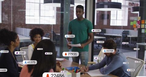 Black team lead presenting during open-plan meeting with digital engagement overlays