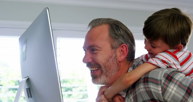 Son embracing father while using desktop pc at home