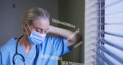 Stressed nurse in hospital corridor with data overlay
