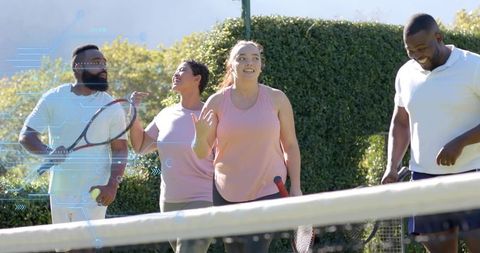 Friends playing walking tennis on sunny outdoor court laughing and socializing for casual fitness