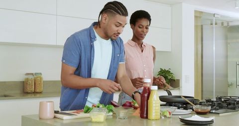 Couple Preparing Meal in Modern Kitchen with Condiments