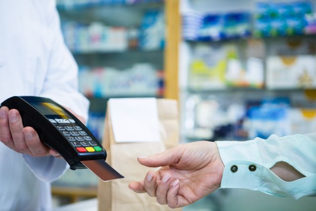 Customer taking credit card from payment terminal in pharmacy