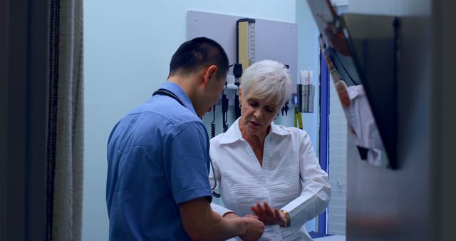 Elderly woman consulting with male doctor in a medical office. They are discussing her health and treatment options. Ideal for healthcare provider websites, medical brochures, senior health articles, and patient care resources.