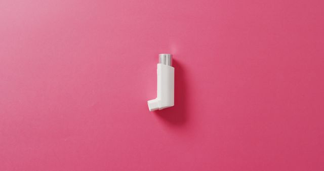 White asthma inhaler placed on bright pink background, emphasizing healthcare and medical treatment. Suitable for articles, medical blogs, brochures, and healthcare-related advertisements highlighting asthma management and respiratory care topics.