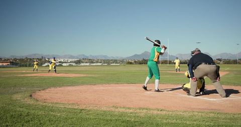 Baseball Batter Preparing Swing at Home Plate with Umpire and Catcher on Sunny Field