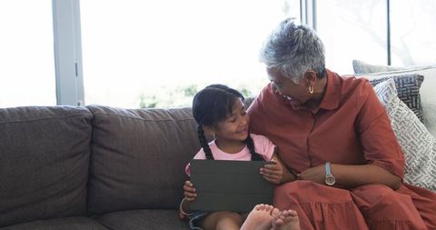 Grandmother and Biracial Granddaughter Sharing Tablet Activity at Home