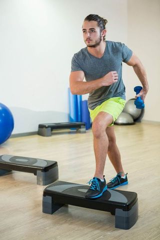 Man Exercising with Step Platform and Dumbbells in Fitness Studio