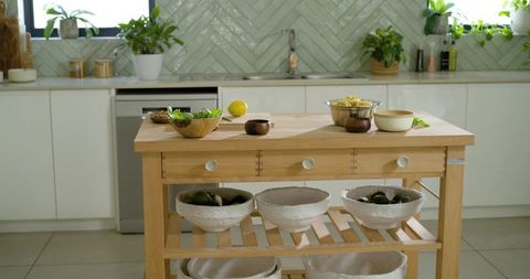 Butcher block kitchen island with open shelves, drawers and herringbone tile backsplash