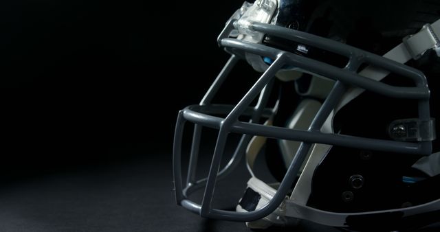 Close up of american football helmet with face guard and copy space on black background. Sports and competition concept.
