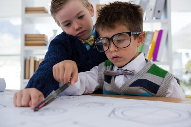 Two young boys dressed in formal attire, including glasses and bow ties, are collaborating on drawing graphs in an office environment. This image can be used to represent concepts such as teamwork, creativity, learning, and the future of business. It is ideal for educational materials, business presentations, and advertisements promoting children's educational programs or creative workshops.
