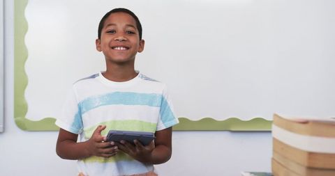 Smiling Boy Holding Tablet In Classroom Embracing Learning