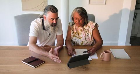 Senior Couple Reviewing Documents over Coffee at Home
