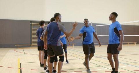 Diverse men's volleyball team shaking hands after match in indoor gym showing sportsmanship