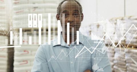 Black warehouse manager analyzing inventory with digital graphs and supply chain dashboards