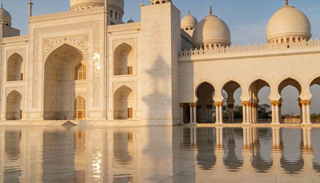 Sunlit white marble mosque facade reflecting on polished courtyard with gold accents
