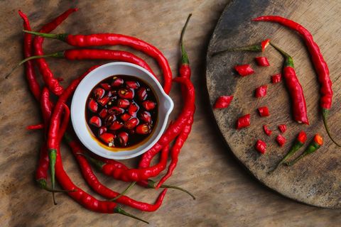 Fresh red chilies and spicy dipping sauce on wooden surface