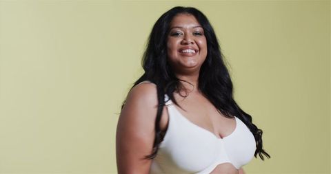 Confident Woman Smiling in White Bra Top on Yellow Background