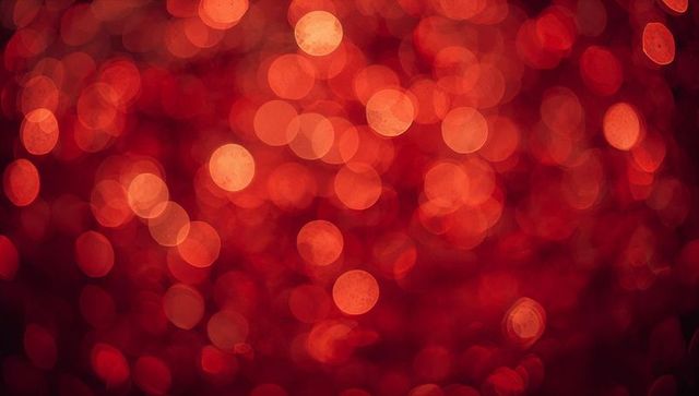 Warm red-orange bokeh backdrop with glittery circles, soft macro blur for festive design