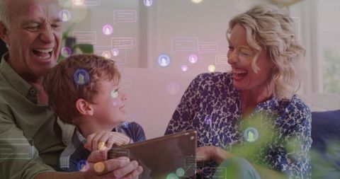 Multigenerational family laughing while sharing tablet with social chat overlays in cozy living room