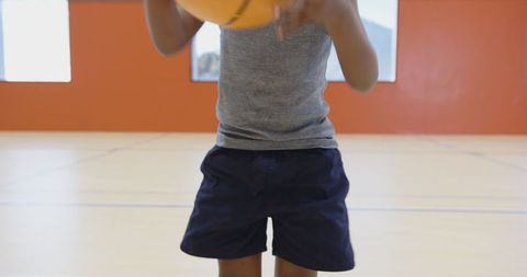 Child Practicing Basketball in School Gymnasium