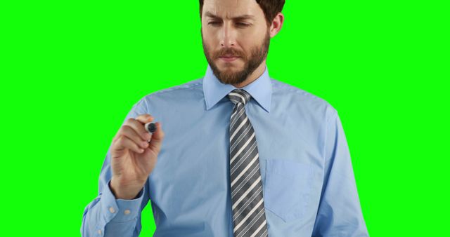 Businessman holding a marker, writing or drawing, on green screen background. Ideal for concepts like business presentations, corporate training, educational videos, and technology demonstrations.