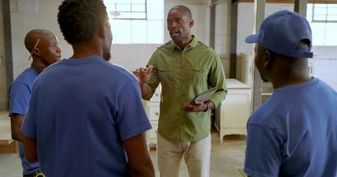 Manager guiding team in workshop with tablet dialogue