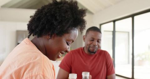 African american couple sharing cozy sunlit breakfast at modern dining table, smiling