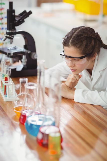 Thoughtful schoolgirl leaning on table in laboratory at school