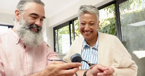 Senior couple checking blood pressure at home with wrist monitor