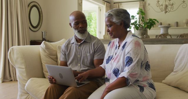 African american senior couple using laptop together while sitting on the couch at home. retirement senior couple lifestyle living concept