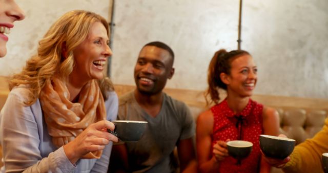 A diverse group of adults is enjoying a warm conversation over coffee, with copy space. Smiling faces and casual attire suggest a relaxed social gathering among friends.