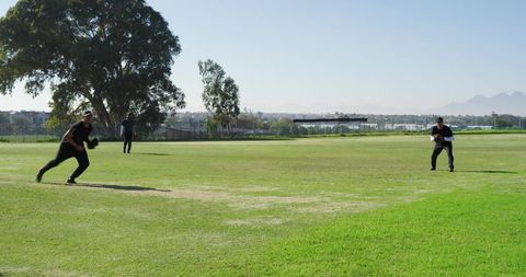 Teammates Practicing Fielding Drill on Sunlit Baseball Outfield for Team Training