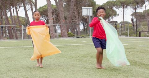 Children joyously running on playground with colorful sheets